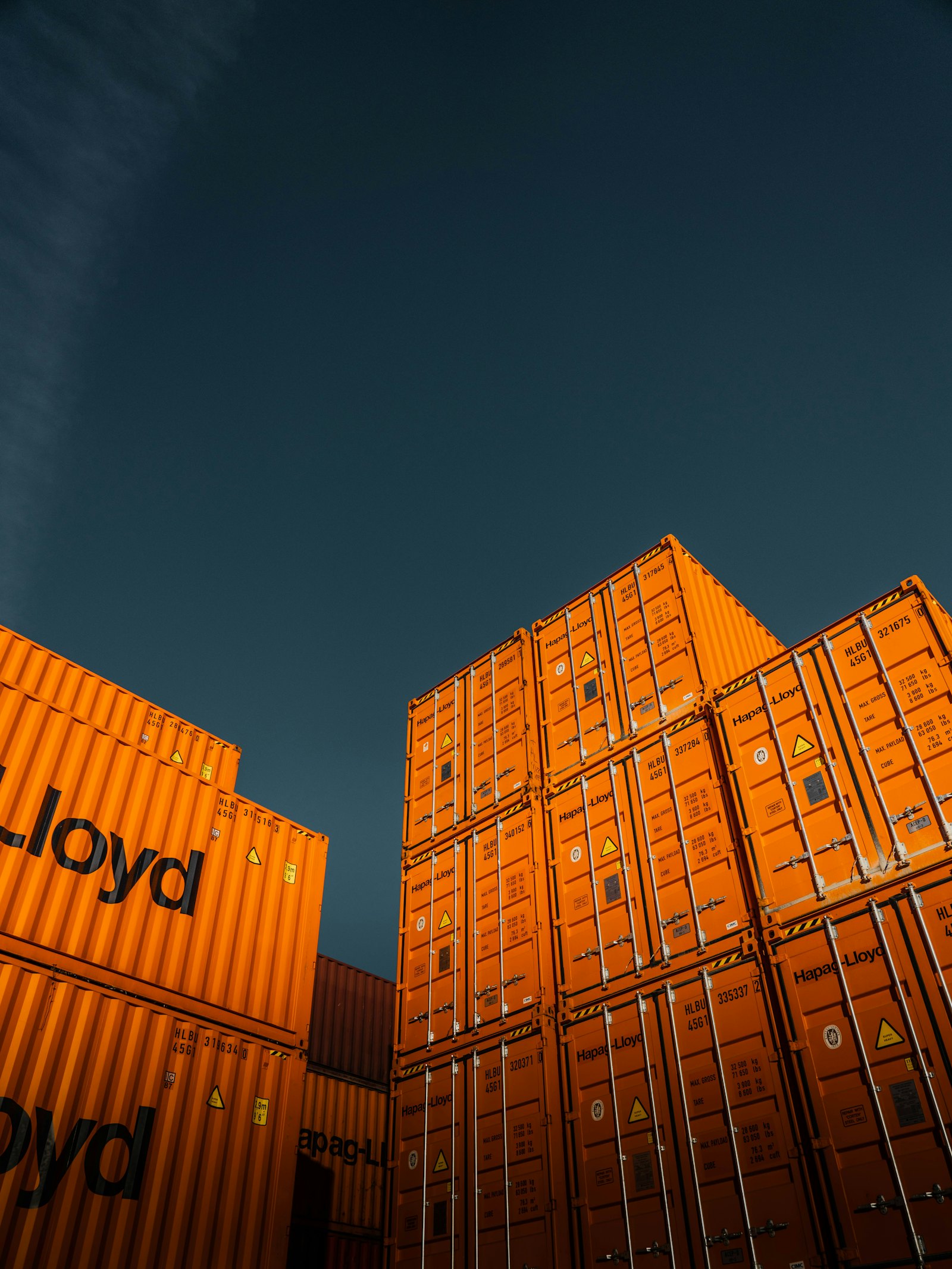 Stacked shipping containers against a deep blue sky